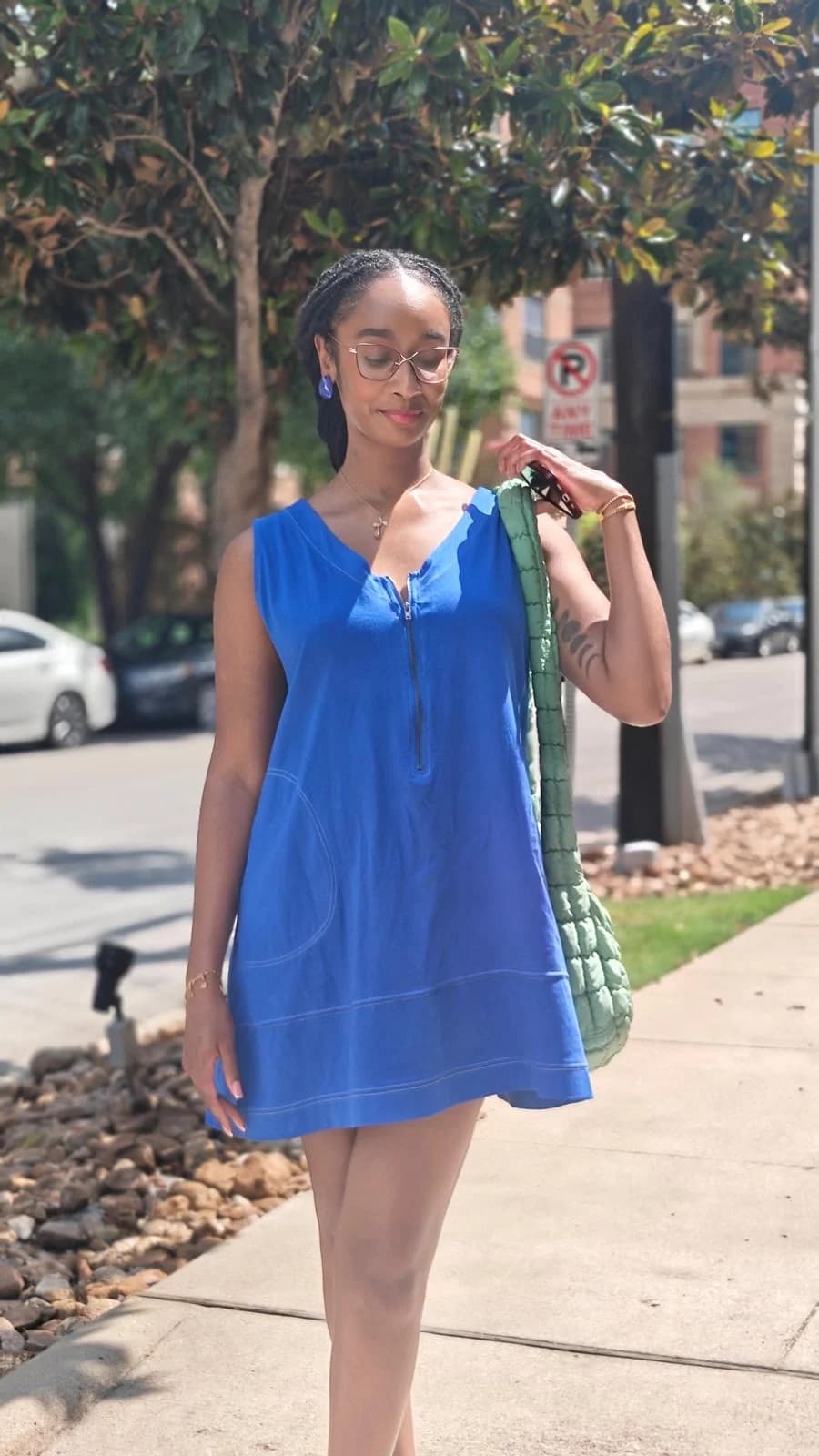 Tayler Martin, founder of Found Together, on a Dallas sidewalk in a blue dress with a sage green bag.